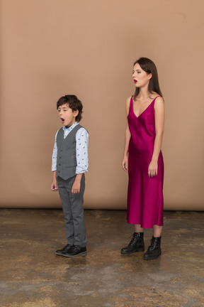 Sleepy woman in red dress and boy in grey suit vest