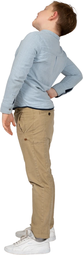Side view of a boy standing with hand on back
