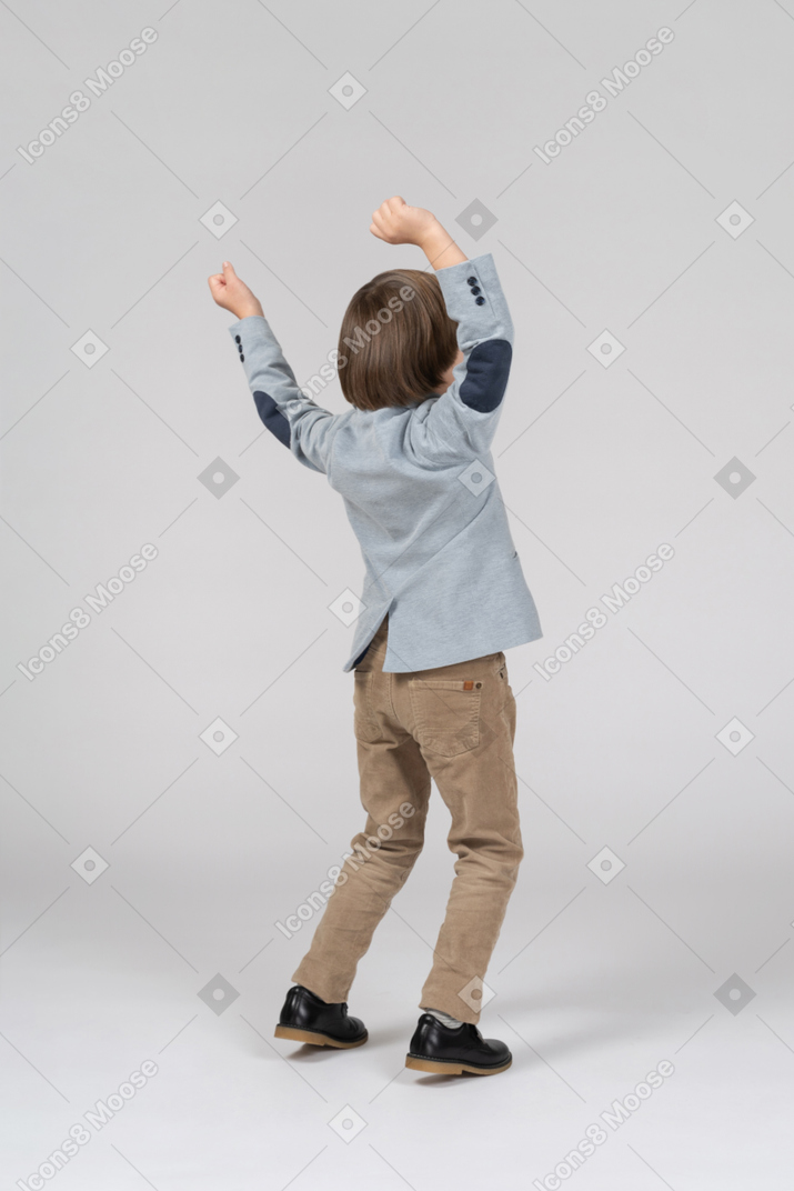 Back view of a boy with hands up
