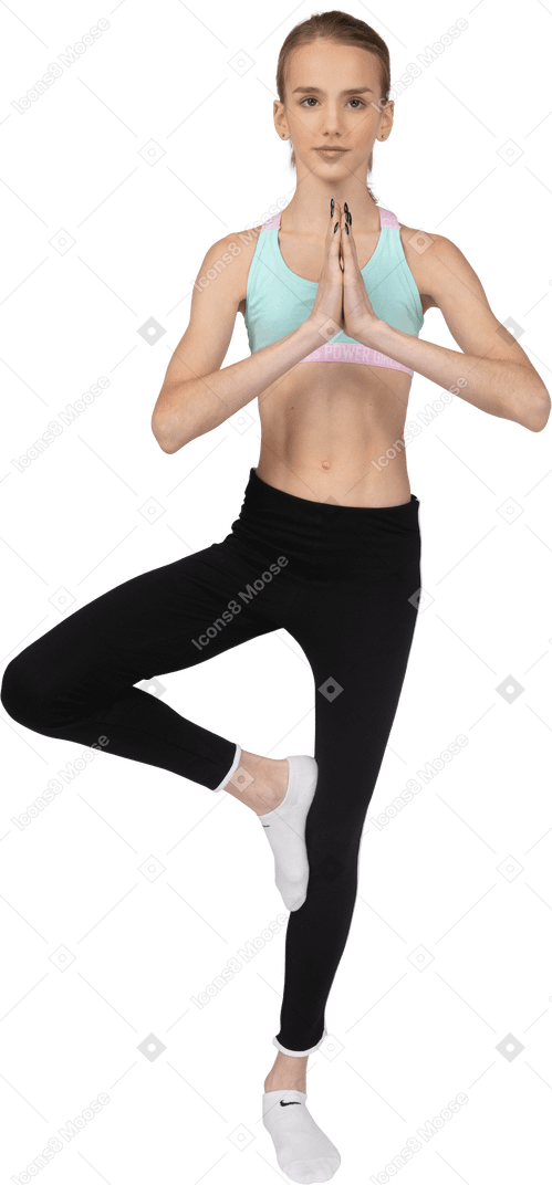 Vista frontal de uma adolescente em roupas esportivas, se equilibrando em uma perna e de mãos dadas