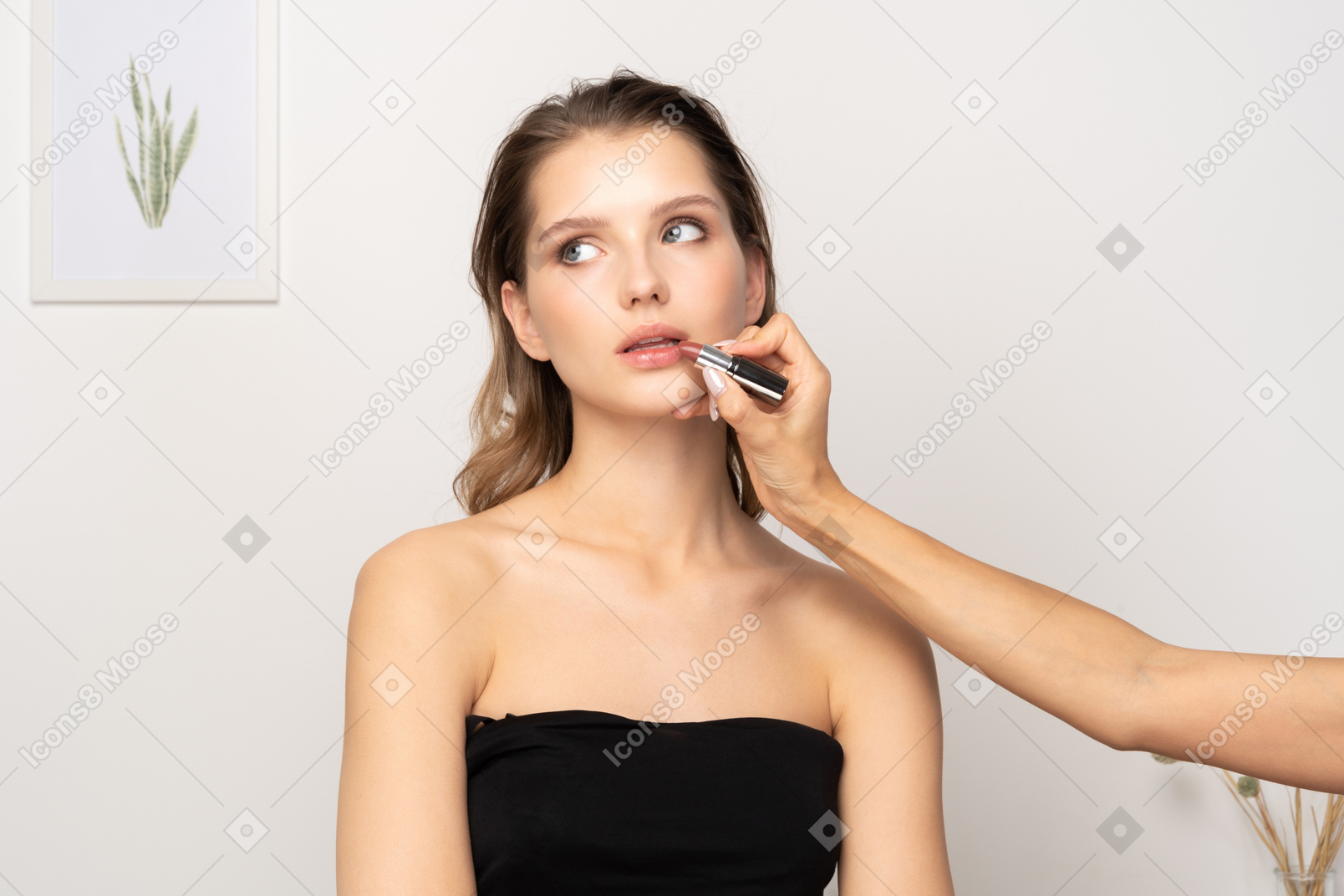 Vista frontal de um maquiador aplicando batom em uma modelo feminina