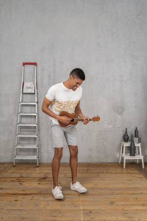 Three-quarter view of a man playing ukulele