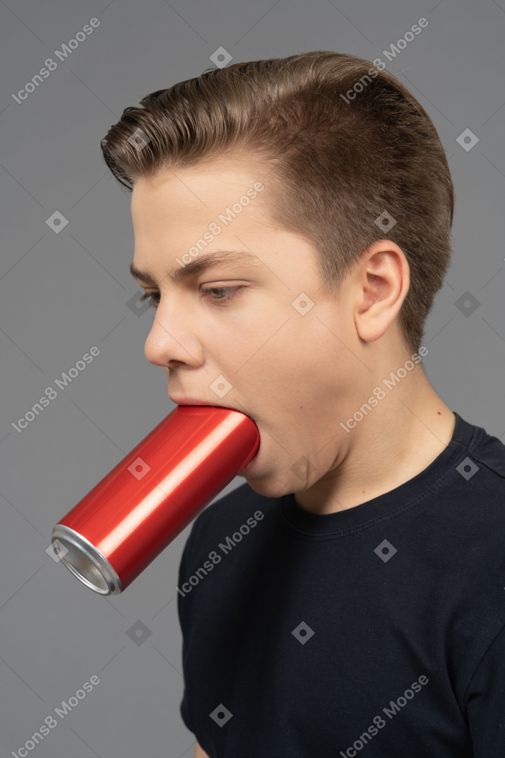 Vista de três quartos de um homem segurando uma lata na boca