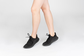 Female legs in black sneakers