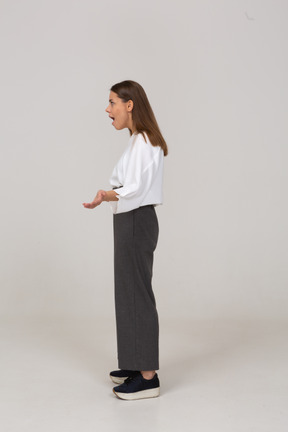 Vista lateral de una jovencita preguntándose en ropa de oficina extendiendo las manos