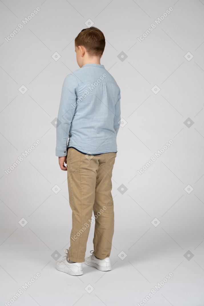 Back view of a boy in casual clothes looking down