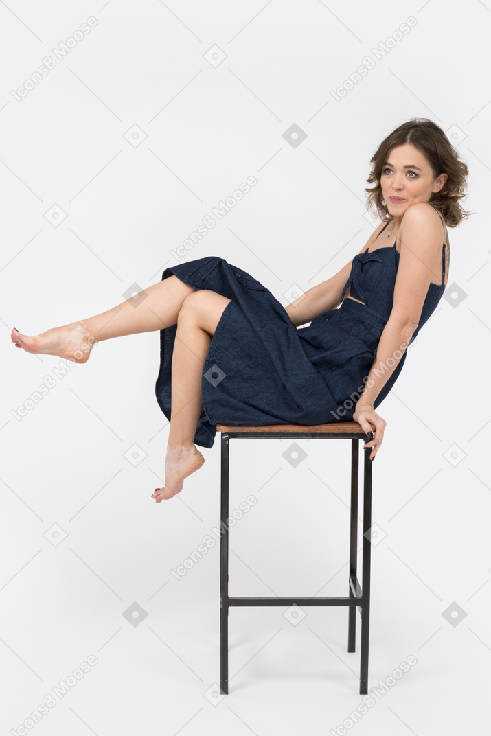 Sensual woman sitting on bar stool in profile
