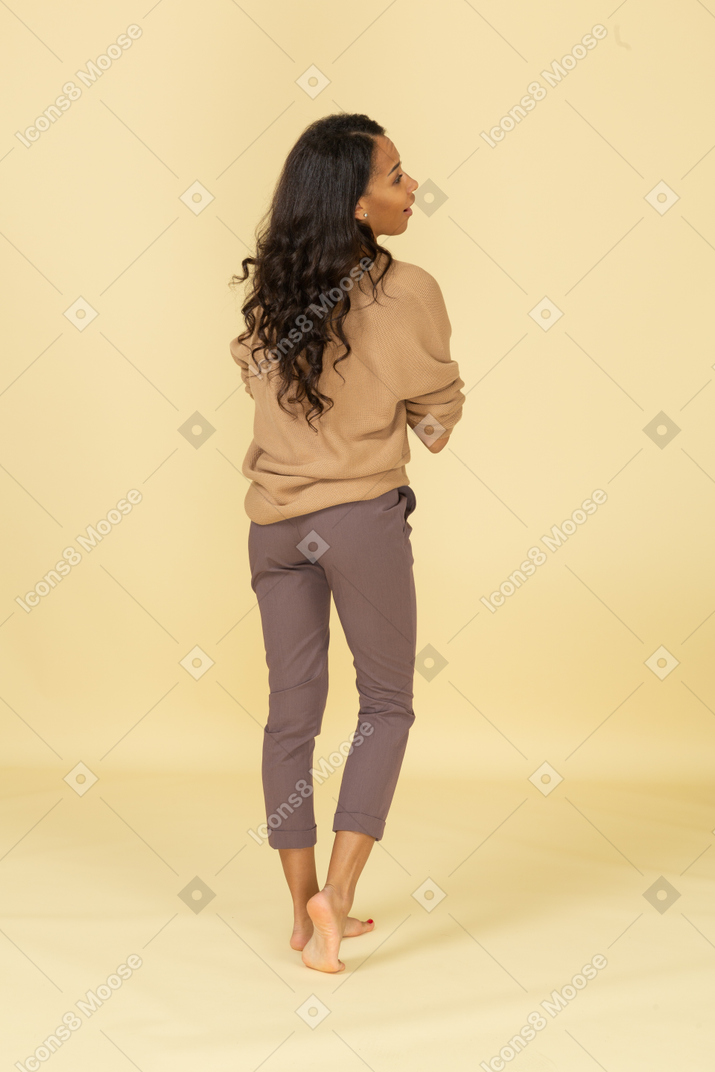 Back view of a pleased dark-skinned young female holding hands together