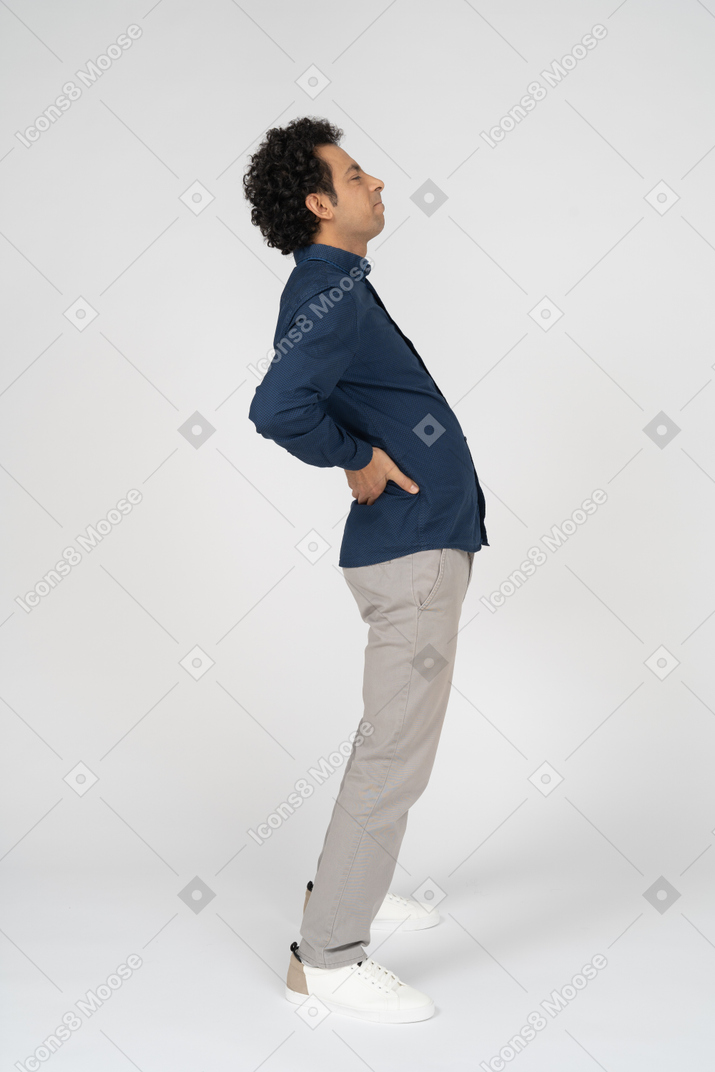 Side view of a man in casual clothes suffering from pain in lower back