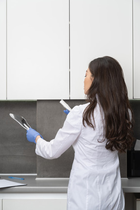 Three-quarter back view a female doctor holding dental instruments