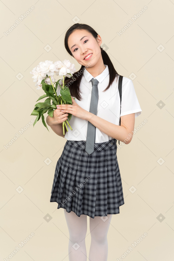 Asian school girl looking attentively on flowers