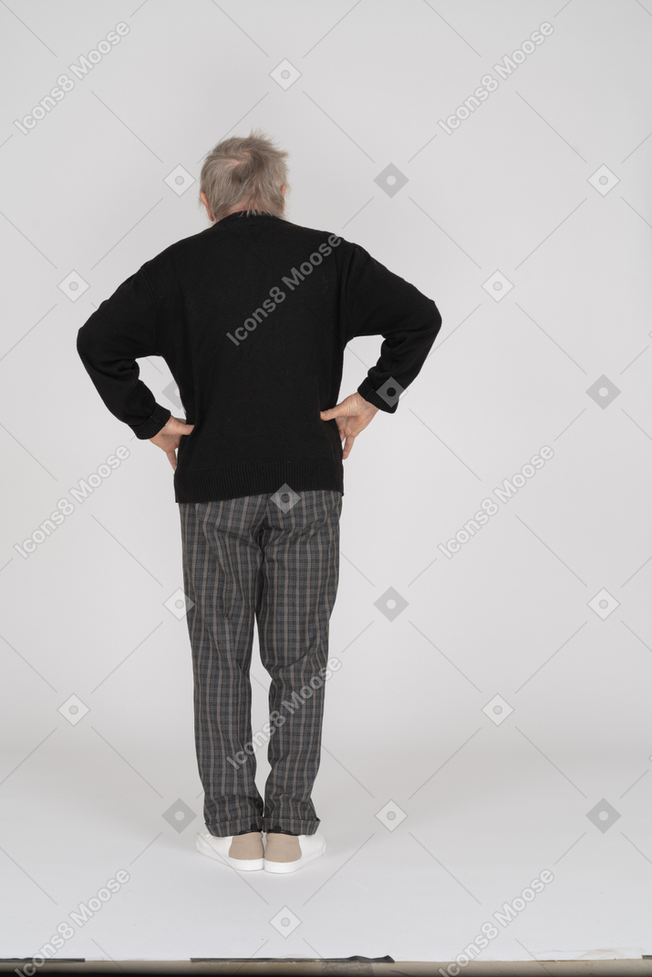 Elderly man with his hands on his hips standing with his back toward the camera
