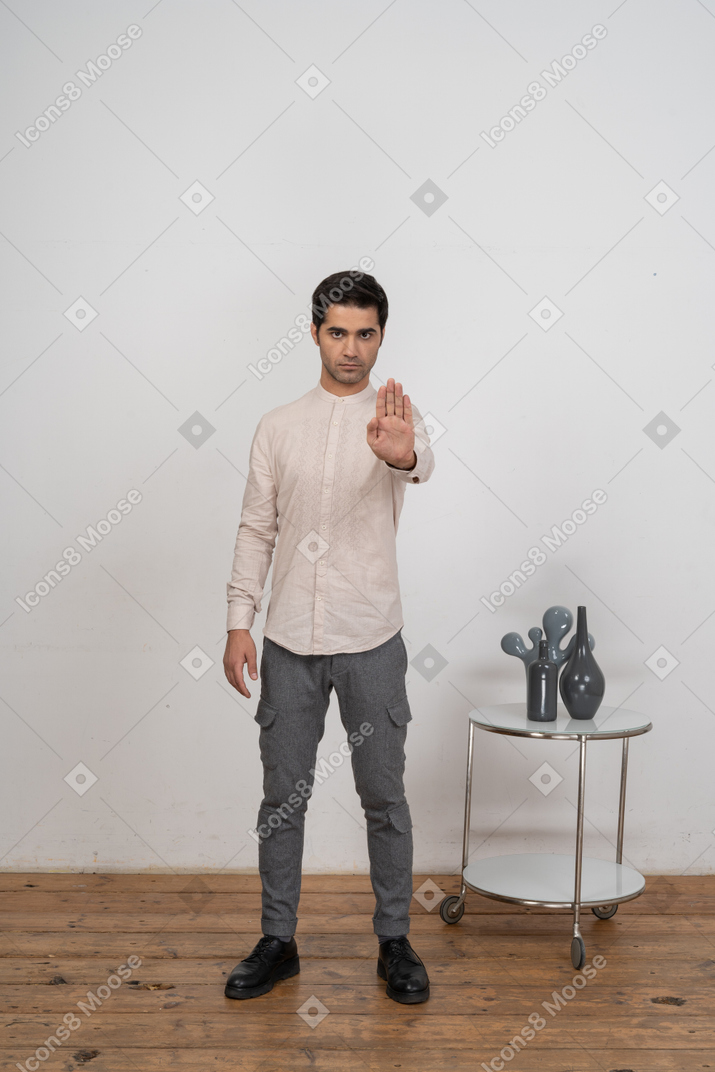 Вид спереди человека в повседневной одежде, показывающего жест остановки
