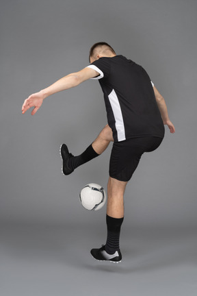 Three-quarter back view of a male football player raising hands and making a stunt