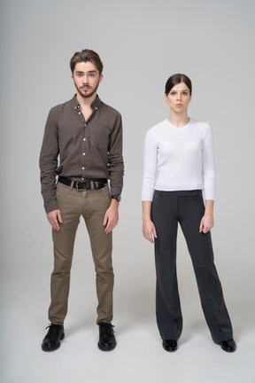 Front view of a young couple in office clothing standing still