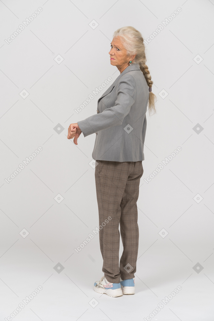 Вид сзади пожилой женщины в костюме, показывая большой палец вниз