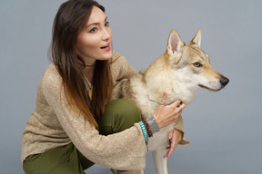 Primo piano di una giovane donna che abbraccia il suo cane e che osserva da parte