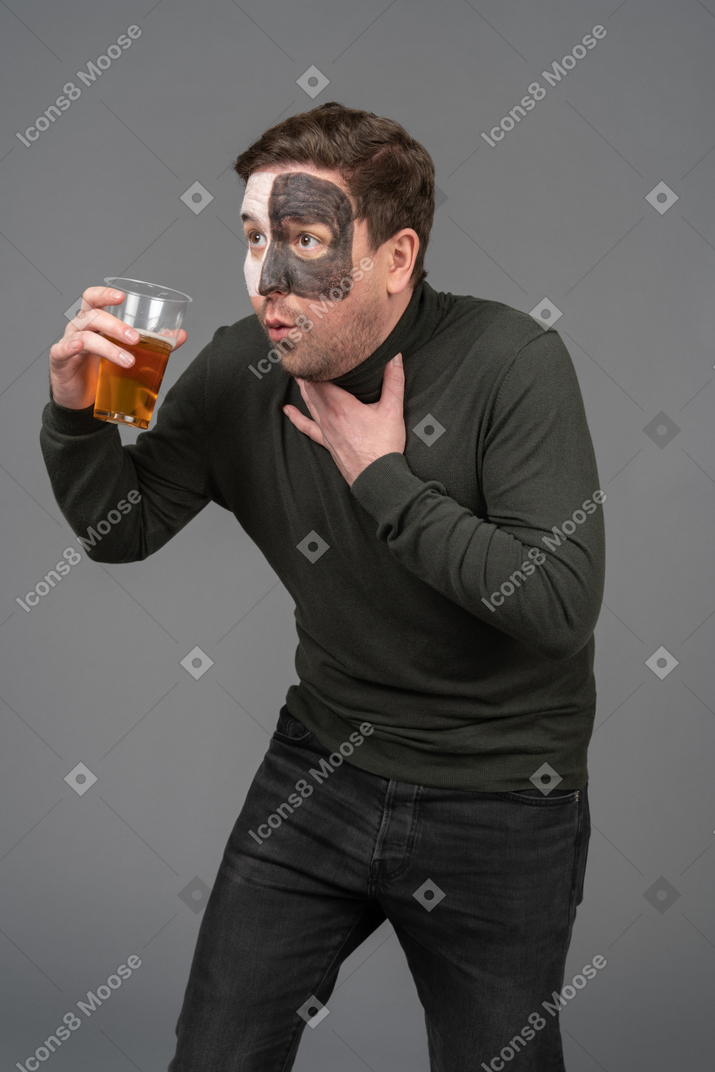 Three-quarter view of a surprised male football fan holding a beer