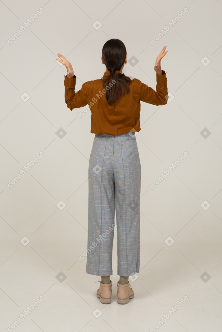 一位身着马裤和衬衫的年轻亚洲女性举手的背影