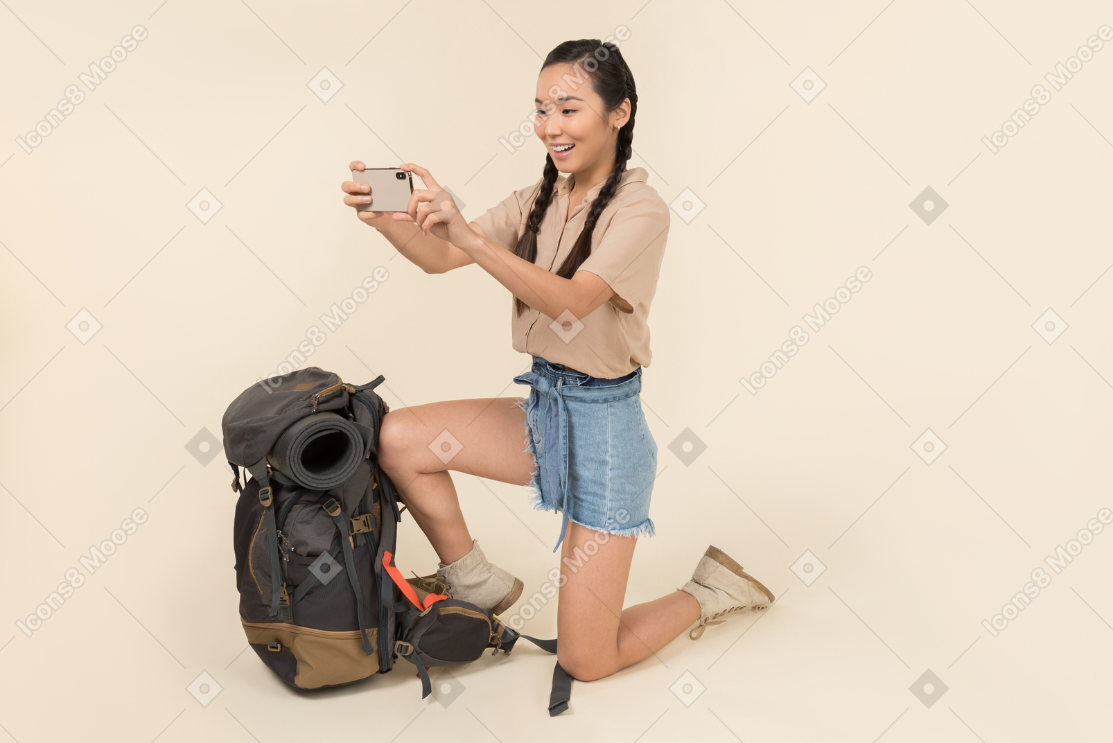 Young asian woman standing near backpack and taking photos