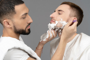 Nahaufnahme eines mannes, der das gesicht seines partners rasiert