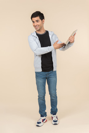 Young caucasian man pointing at a digital tablet he's holding