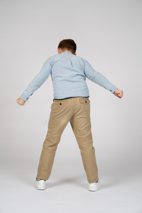 Vista posteriore di un ragazzo in piedi con le braccia tese