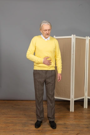 Front view of an old man having a stomach ache