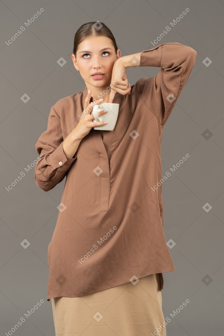 Young woman dipping her finger in a mug and looking up
