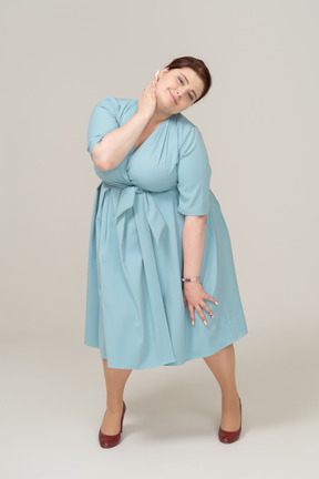 Vista frontale di una donna in abito blu in posa con la mano sul collo