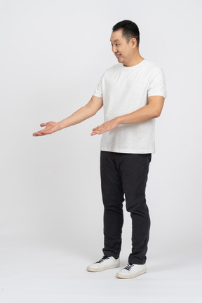 Dreiviertelansicht eines mannes in freizeitkleidung, der etwas interessiert betrachtet und mit einer hand zeigt