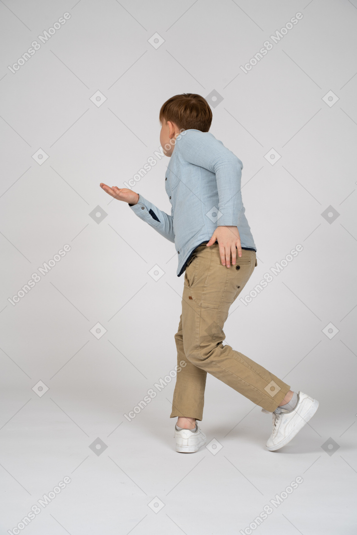 Back view of a young boy reaching his hand out