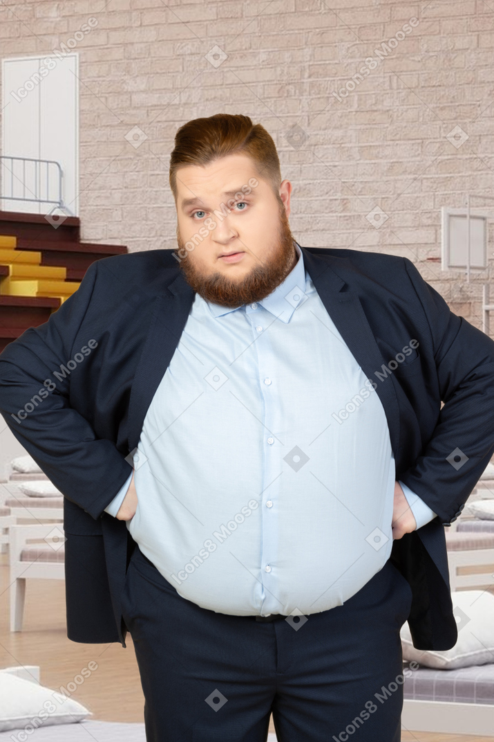 A fat man in a suit standing in a basketball court with beds